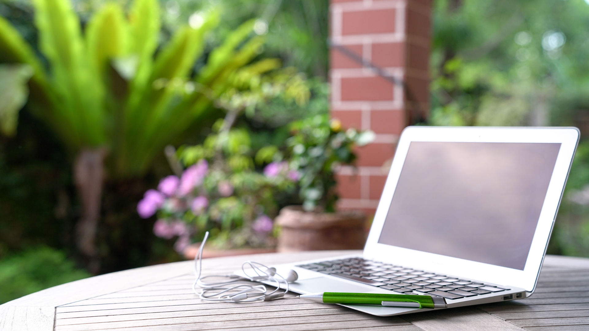 laptop on home patio with nice flowers and headphones 